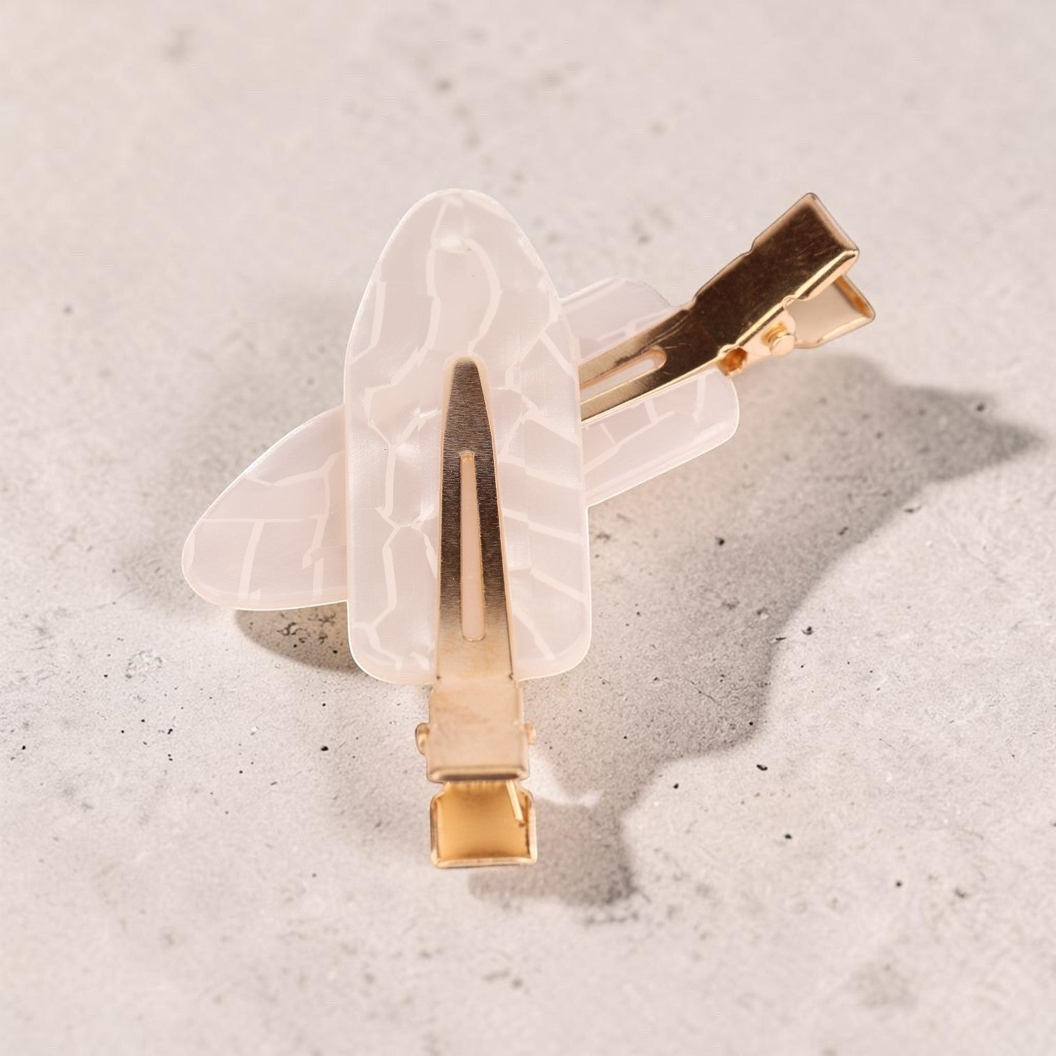 Translucent white acrylic resin hair clip with gold-tone metal hardware and leaf-shaped design