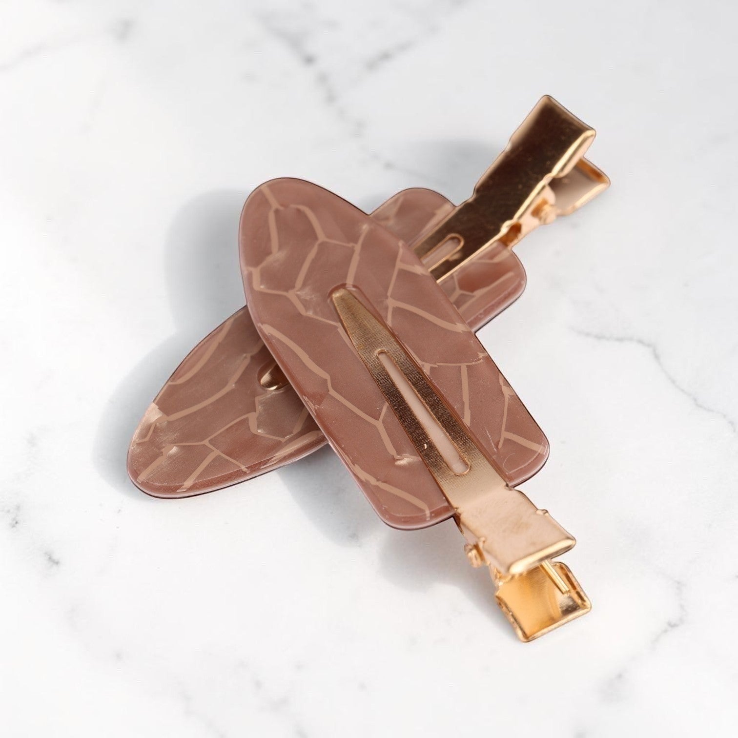 Mauve acrylic resin hair clip with geometric leaf pattern and gold-tone metal clasp on marble background
