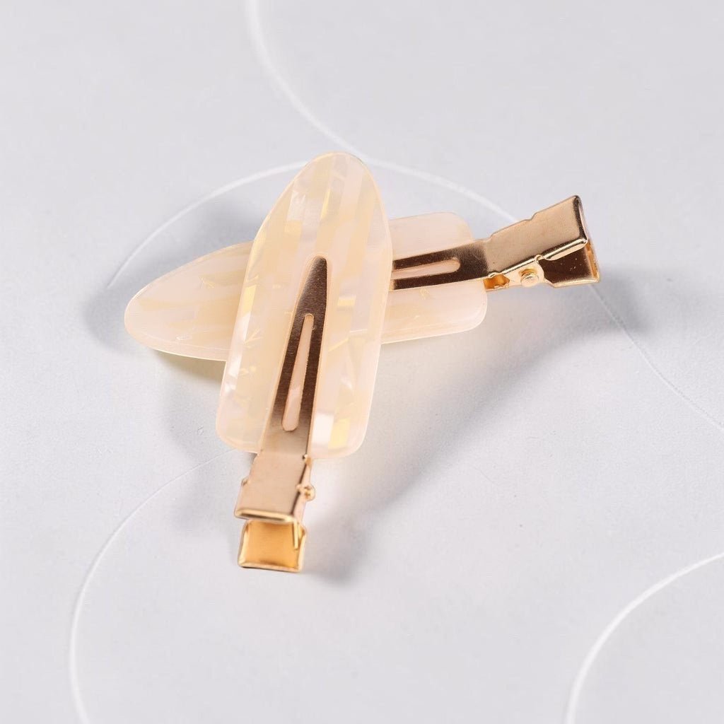 Cream acrylic resin hair clip with gold-tone metal clasp and rectangular accent detail