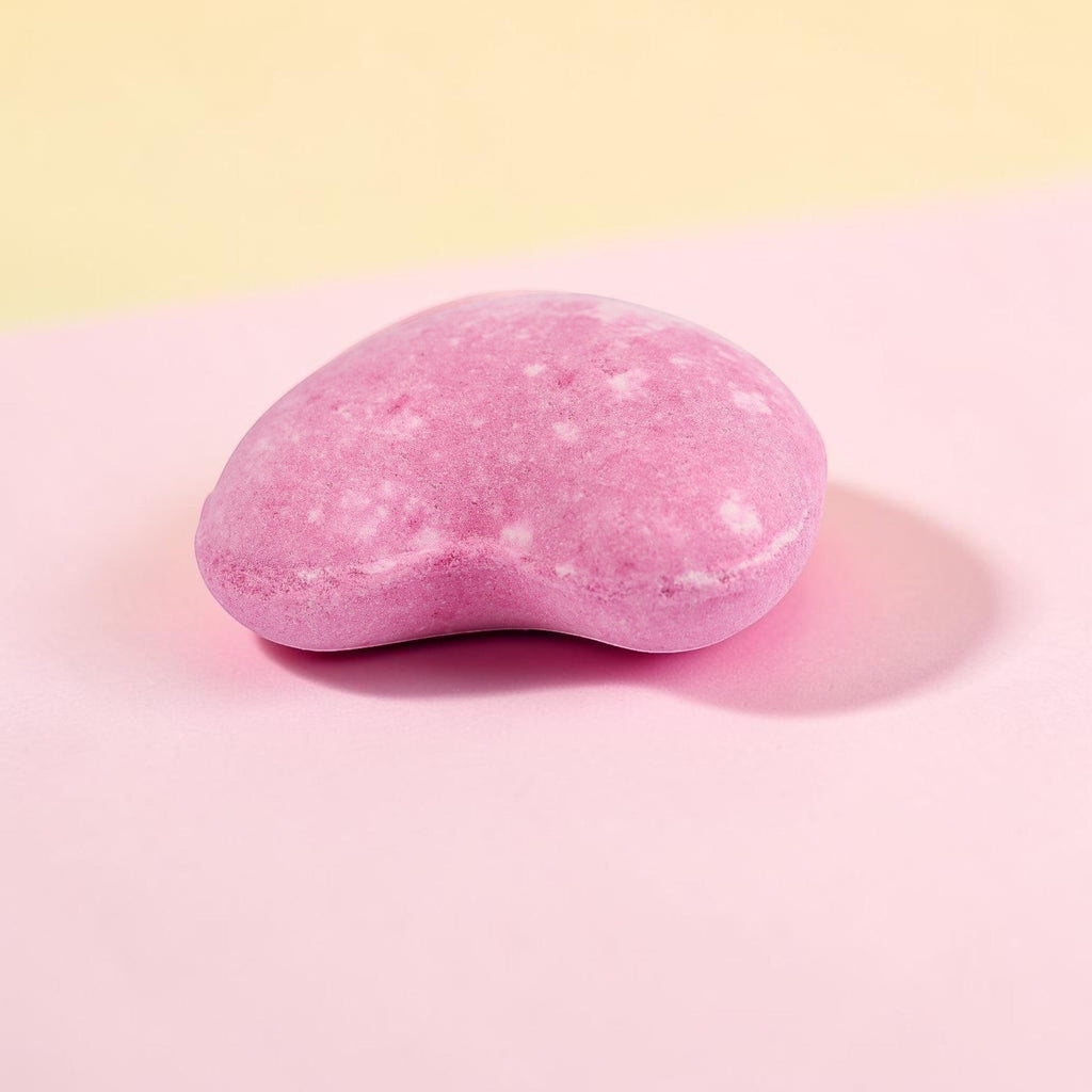 Pink oval bath bomb with shimmering finish on soft gradient background
