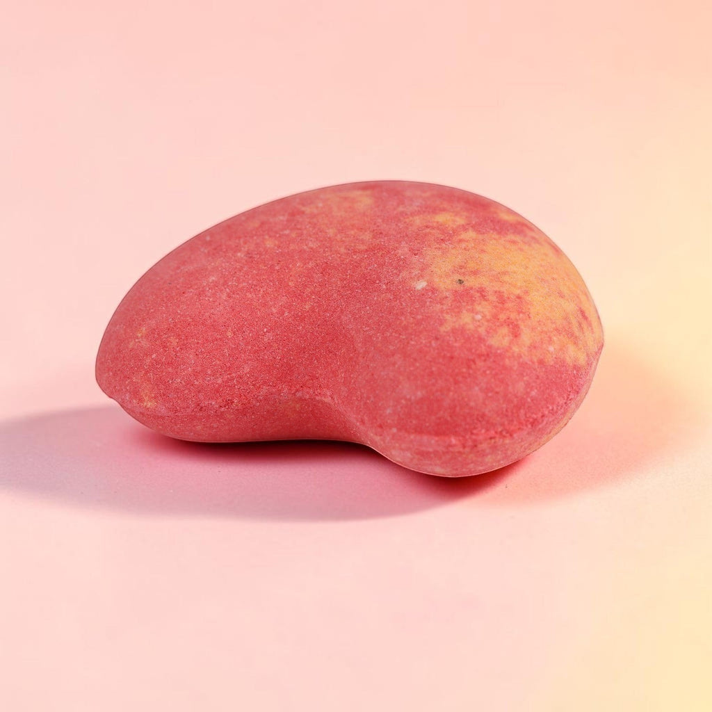 Red and gold ombre bath bomb with organic vegan formula on pink background