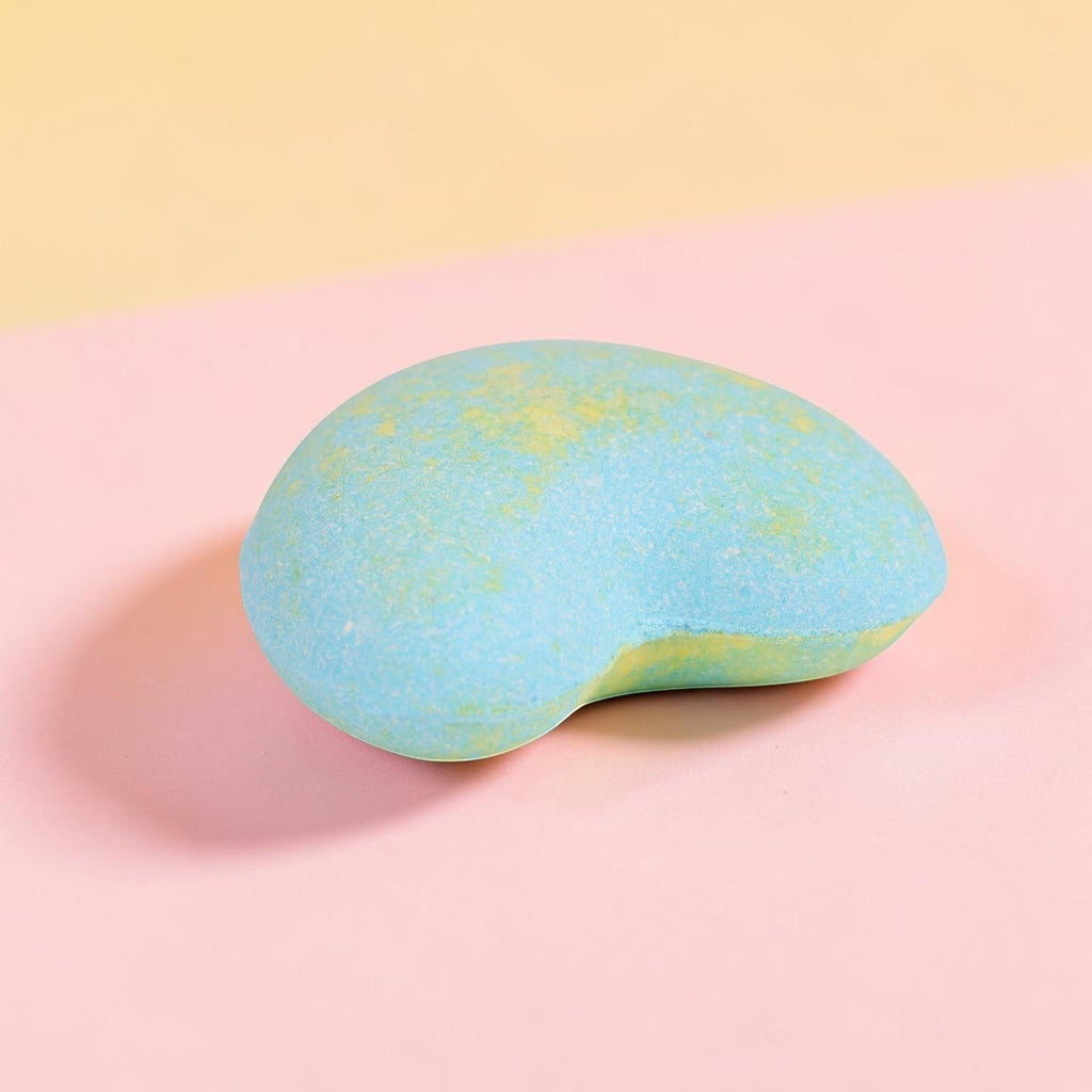 Turquoise and yellow speckled bath bomb with organic vegan formula on pink background