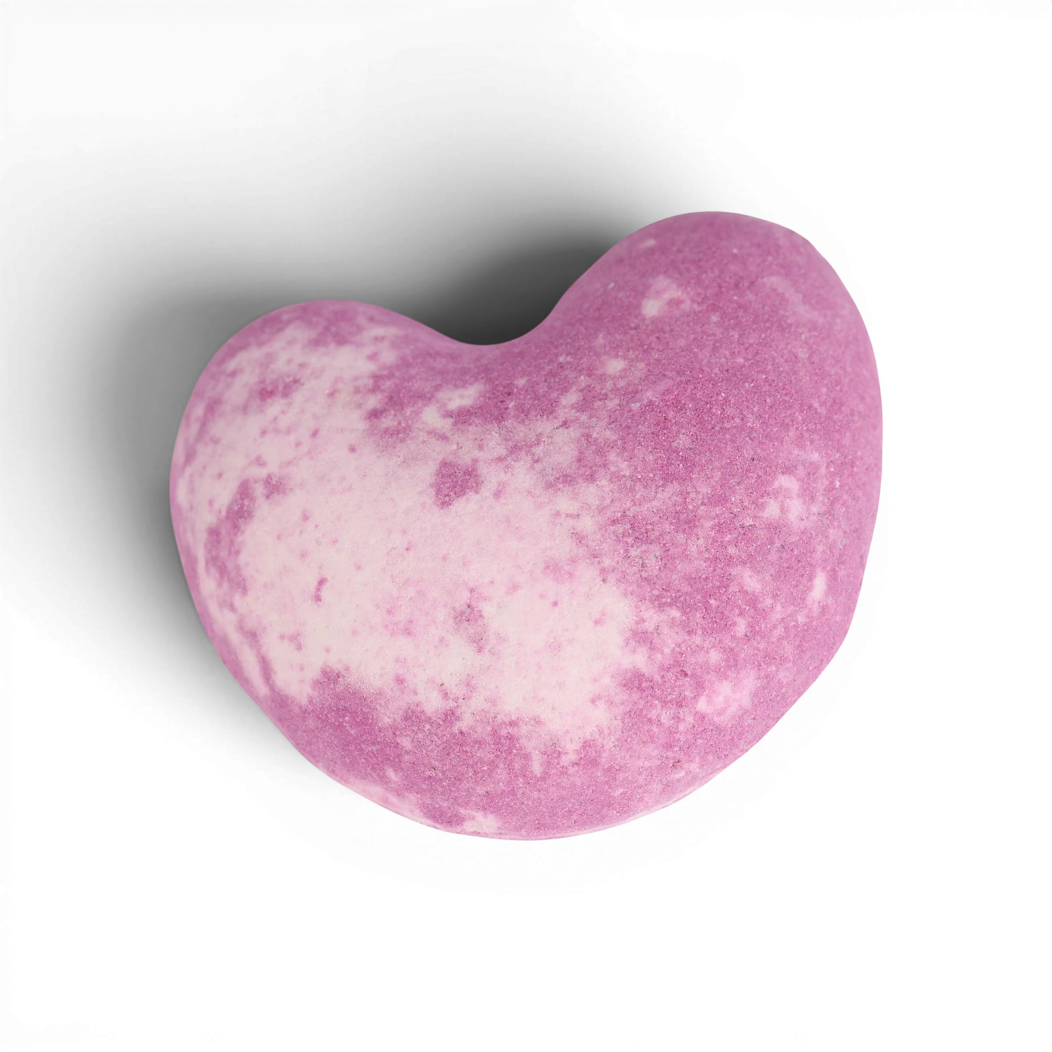 Pink heart-shaped bath bomb with speckled texture and skin-nourishing oils
