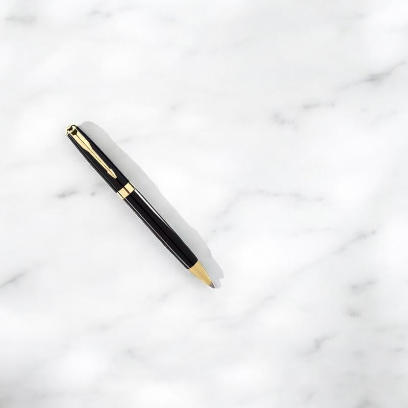 Bolígrafo Boxigami negro brillante con detalles dorados, acabado lacado, ideal para regalo.