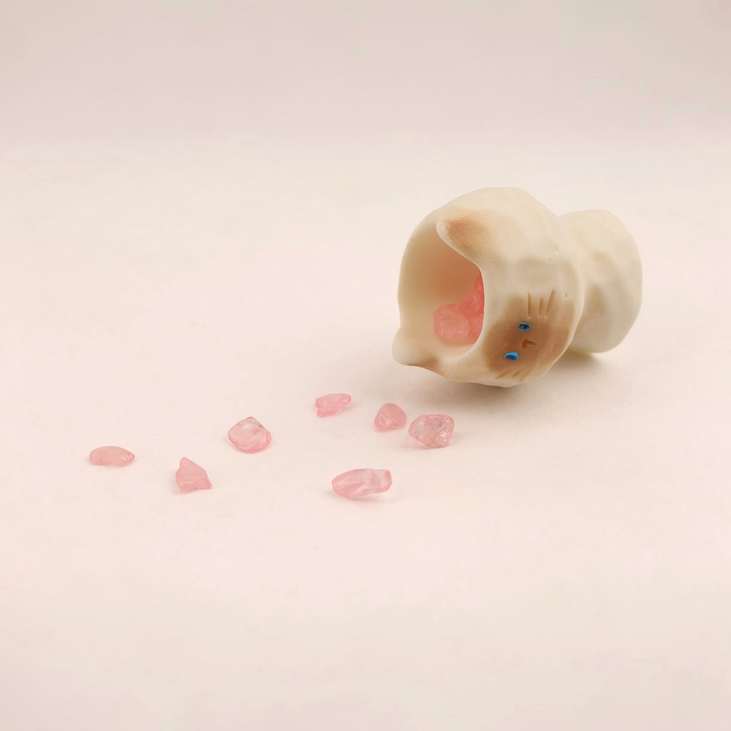 Figura de gato de Boxigami con acabado de cristal pulido, que derrama cristales rosas. Un adorno juguetón para escritorio.