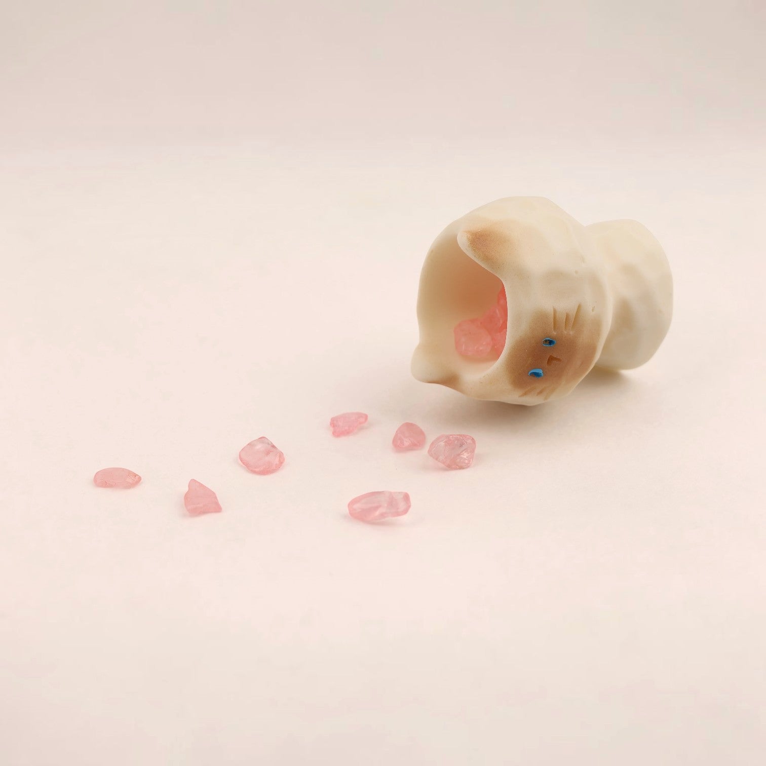 Figura de gato de Boxigami con acabado de cristal pulido, que derrama cristales rosas. Un adorno juguetón para escritorio.
