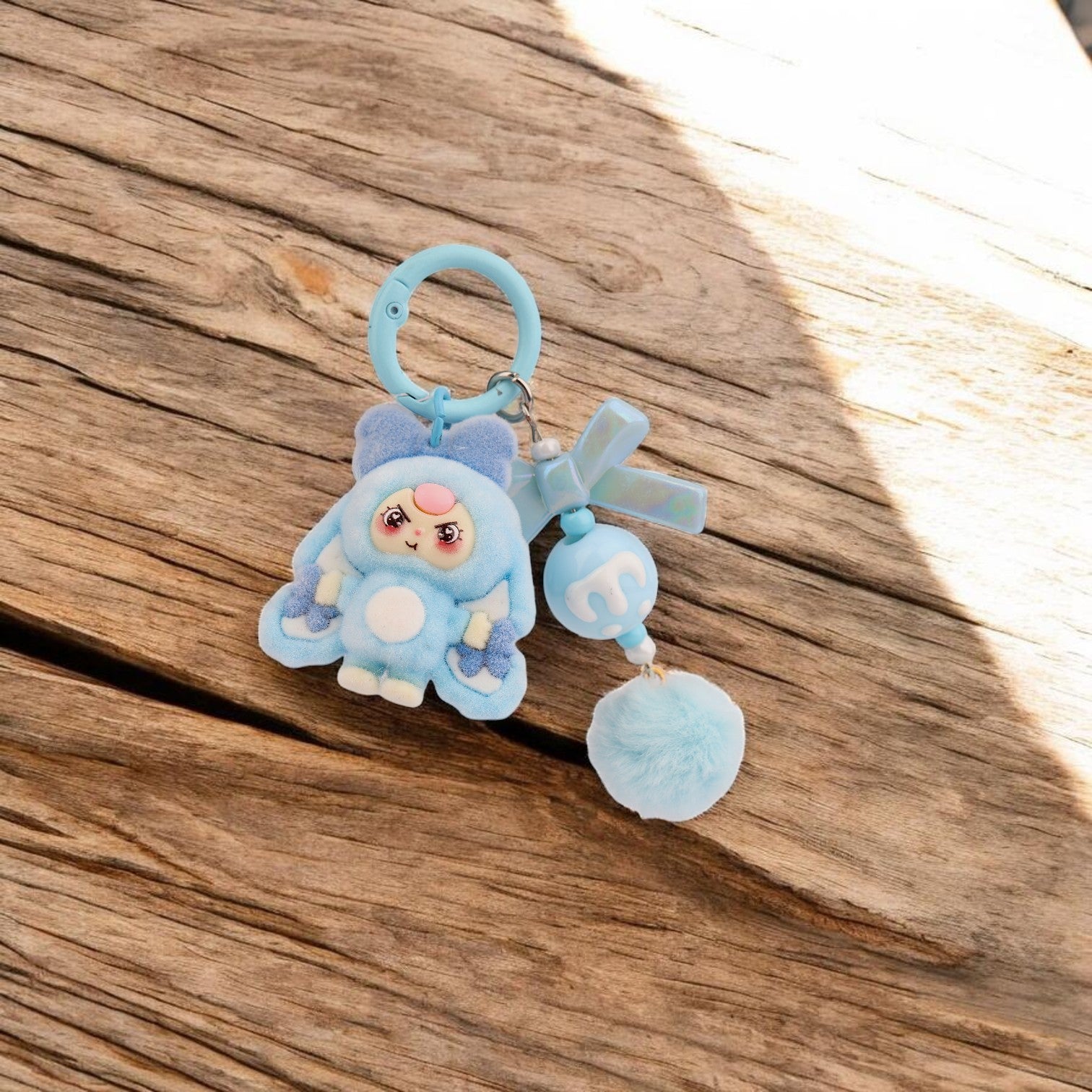 Boxigami llavero de peluche azul con forma de conejo, pompón y detalles de lazo.