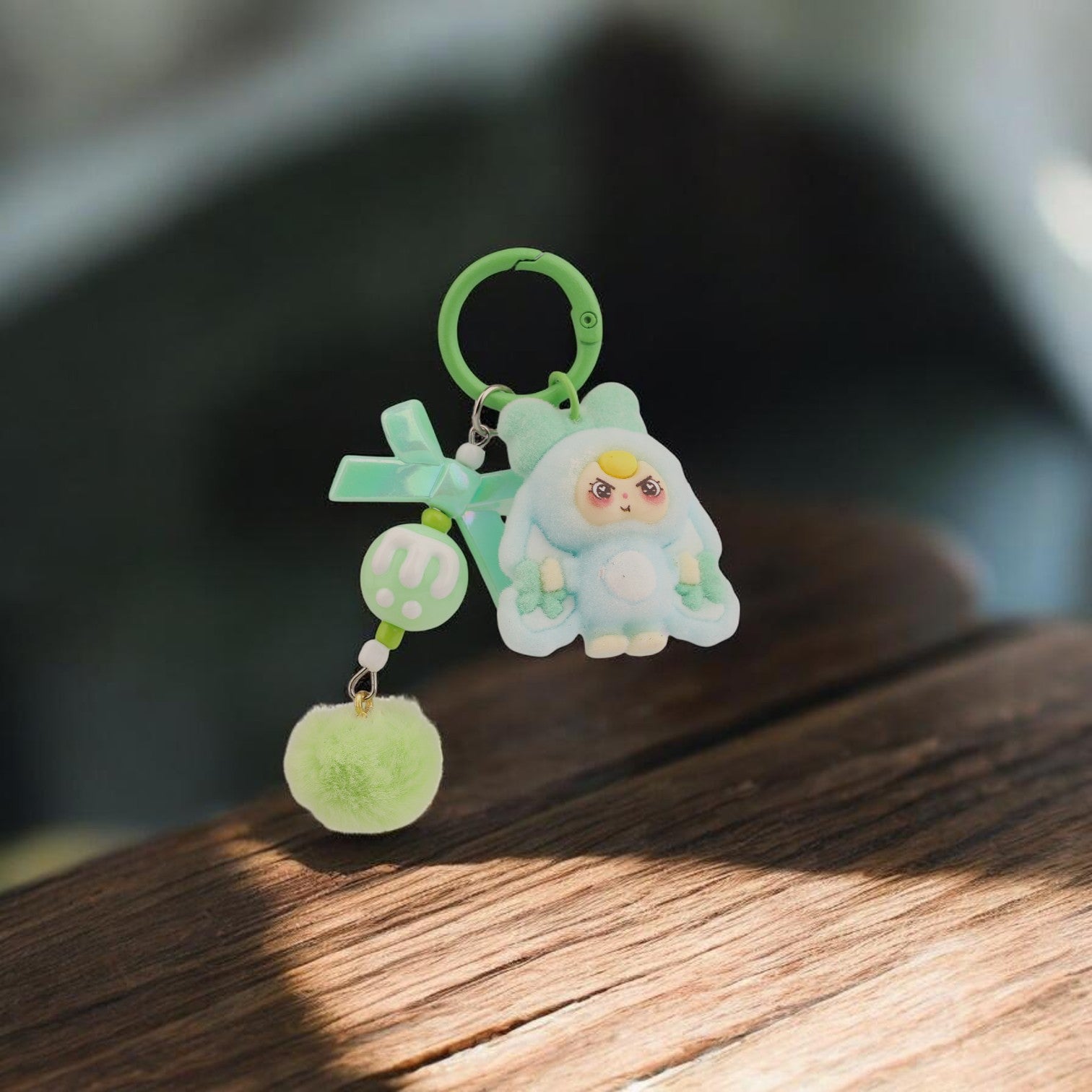 Boxigami llavero de peluche azul con forma de conejo, pompón verde y detalles de lazo.